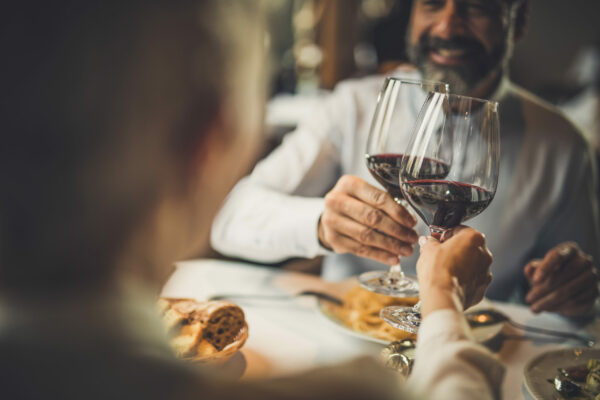 Close up of a couple toasting with red wine during lunch in a restaurant.
